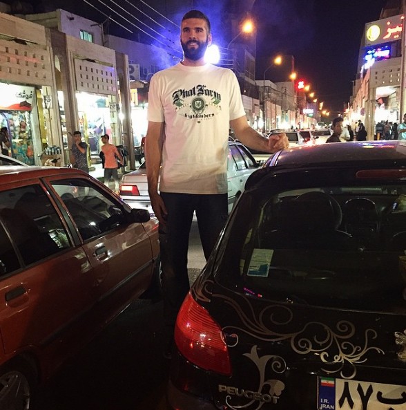Slavko Vraneš standing as a giant beside cars