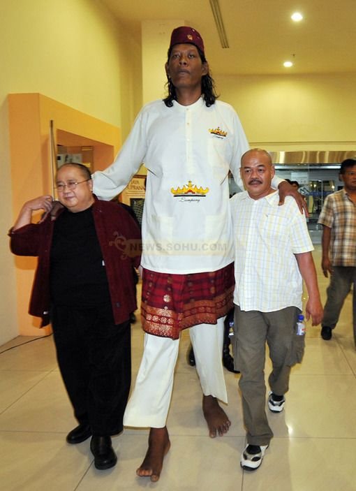 Gigantic Suparwono walking with two men